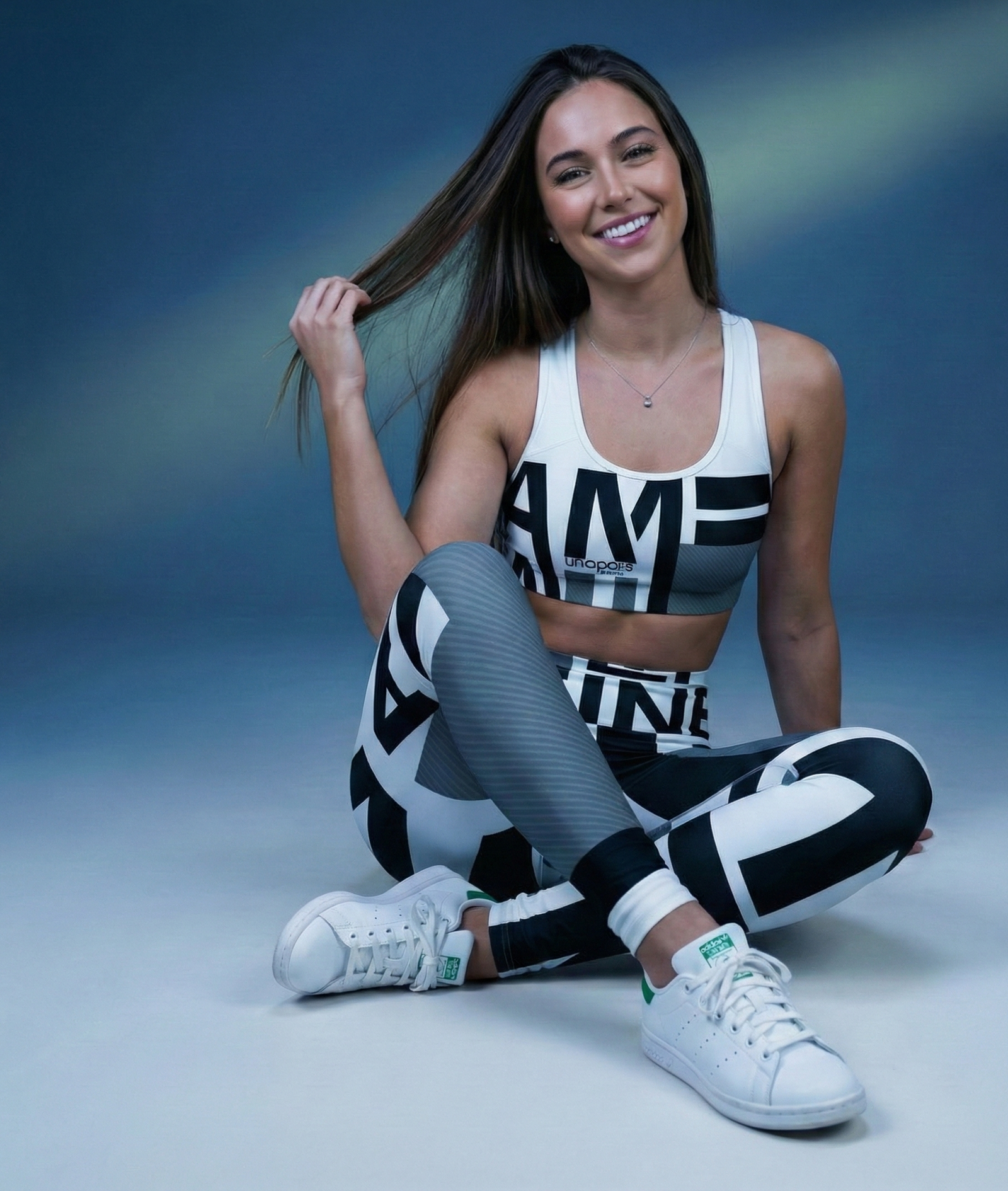 Woman in athletic wear sitting on the floor with a blue gradient background